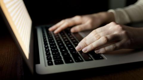  Woman's hands using laptop at office desk