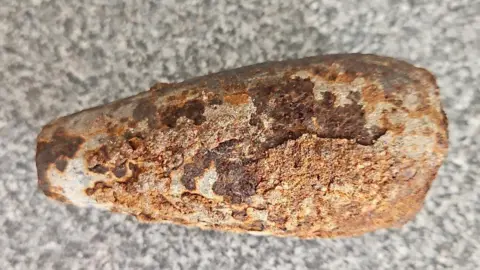 A rusted object on a grey and white speckled background. 