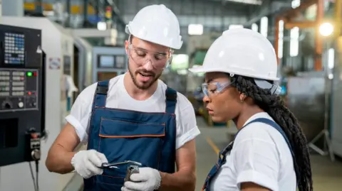 Two engineers wearing white helmets looking at equipment