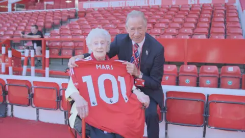 Nottingham Forest An older lady with a red football shirt saying Marj 101 on the back