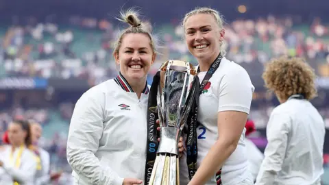 Marlie Packer and Rosie Galligan pose for a photograph holding the RWC trophy 