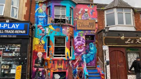 The front of a pub with a colourful mural covering it's entirety