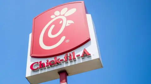 The red and white Chick-fil-A sign against a bright blue sky