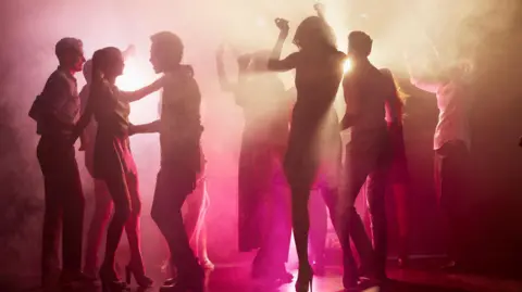 Getty Images Silhouetted people dancing on a nightclub floor