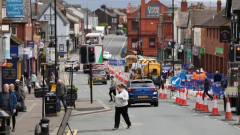Reuters The high street in Ashton-in-Makerfield with pedestrians and roadworks.