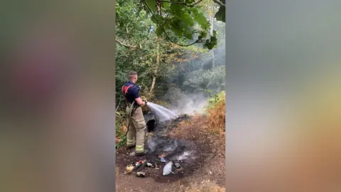Leicestershire Fire and Rescue Service Firefighter with a hose tackling a fire