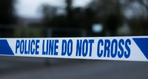 Police tape in white and blue reading "police line do not cross"