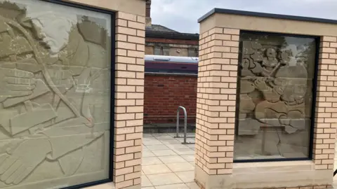 The Kiddey Stones sculptures enclosed in structures in front of a brick wall