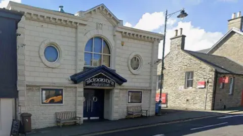 A nightclub entrance in Thurso with a light brick building and a blue archway over the door with the name Skinandi's on the top