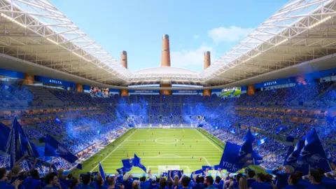Birmingham City Dentro del terreno hay un mar azul donde los fanáticos se sientan en la impresión de este artista. Se puede ver el terreno de juego con los jugadores sobre él. Pantallas publicitarias rodean el anillo superior alrededor del suelo, que está parcialmente cubierto por un techo blanco.