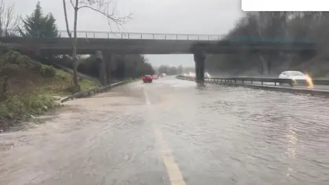 Water on the M1 motorway, close to a bridge. cars on the road.