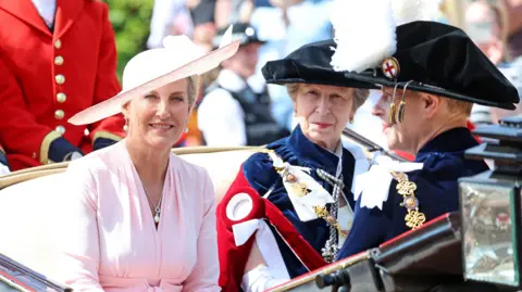 PA Media The Duchess of Edinburgh, the Princess Royal and the Duke of Edinburgh depart the service by carriage. Sophie is in a pink dress and pink hat, the others wear garter robes.