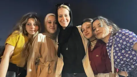Family Handout Hayat is standing with her four daughters, she is wearing a black headscarf. They are all smiling. 