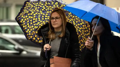 Getty Images Danielle Sassoon holds an umbrella