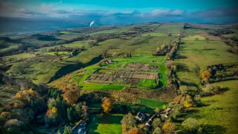 Vindolanda Trust An aerial shot of the Vindolanda Fort which stretches over a large site. Beyond it the fields of the Tyne Valley stretch into the distance 