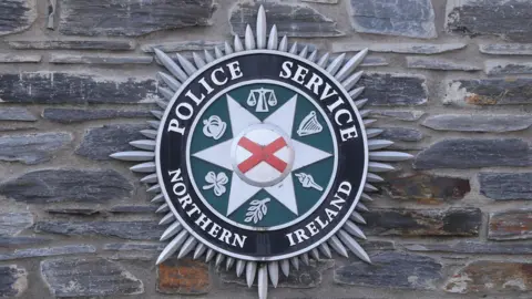 PSNI logo on a gray stone wall