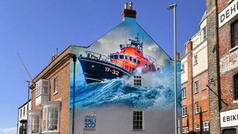 Artist's impression of proposed mural showing a lifeboat in rough seas covering the upper half of a three-storey building on a street corner