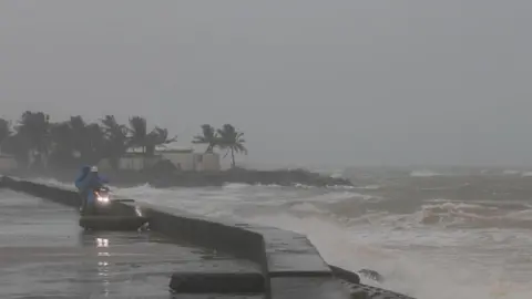 EPA Image shows people watch waves crashing on the beach ahead of Typhoon Kalmaegi in Cua Dai, Da Nang, central Vietnam, on 6 November 2025 