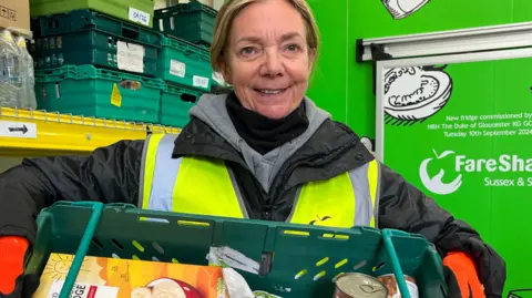 A woman holds up a crate of food