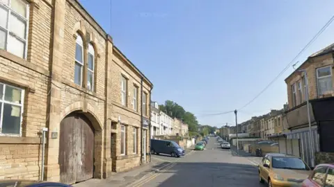 Google A residential street with an industrial building.