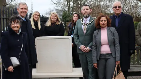 People standing around a memorial headstone