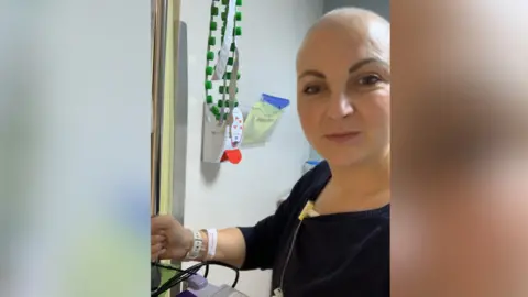 Supplied A woman looking at the camera. She is hooked up to machines and has hospital bands around her wrist.