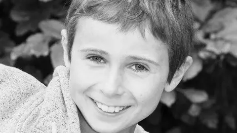 Family handout A black and white image of Robbie Keville. He is grinning and looking at the camera, he has short hair and is wearing a speckled hoodie. He is standing in front of some hedging.