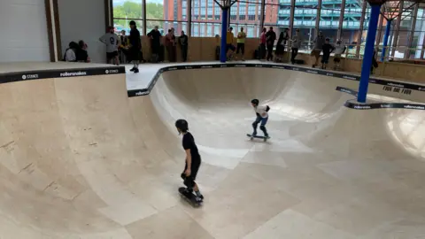 Skaters using a bowl inside a new indoor skatepark