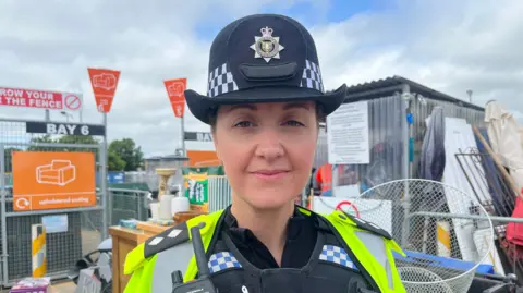 Inspector Amanda Hart is standing in front of a number of items of rubbish at a household waste recycling centre in Sussex