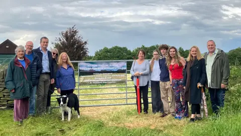 People standing at a farm either side of a banner rejecting plans for a housing estate