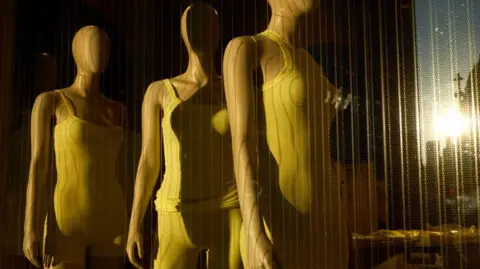 Getty Images Três manequins exibindo os modeladores de Skims atrás de uma vitrine em uma loja pop-up em Nova York