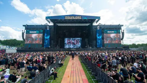 Getty Images The main stage at Download Festival, the crowd is split down the middle. Crowds of people are watching the stage stood and sat on the grass. 