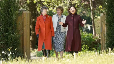 Reuters The Princess Royal is shown the garden by Dr Linda Yeuh, Chair of The Royal Parks. Three women walk through a garden
