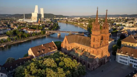 A drone view shows the Basel Muenster Cathedral above the Rhine river.