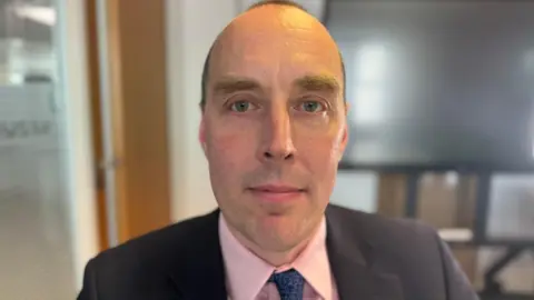 Charlie Rose/BBC Paul Stanley, from the British Transport Police, is wearing a pink shirt and a dark suit and tie as he looks at the camera. He is slim with little hair and appears middle aged.