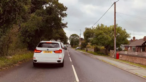 John Withers A line of cars queuing on the road towards Macclesfield household waste recycling centre.