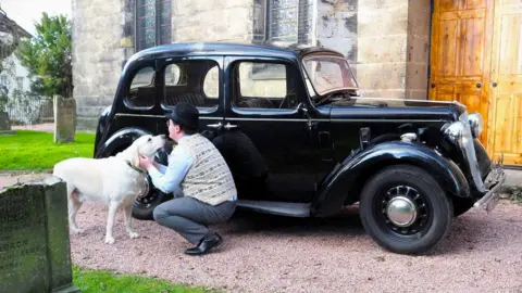Ron Walker Callum petting his dog beside his car