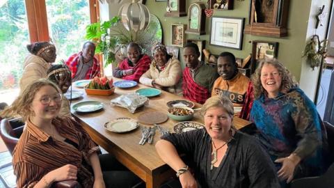 Jeni and Karen with the Maasai dancers at a dinner table 