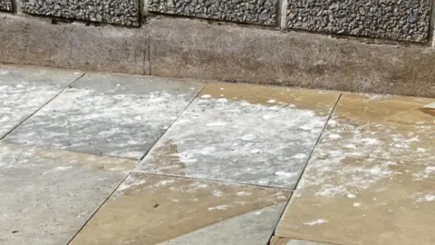 A pavement in Scarborough that is filled with white bird droppings