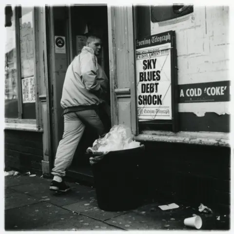 Jason Scott Tilley/Lower Block A boy looks towards the camera as he enters a shop. He has short hair and is wearing a tracksuit. An Evening Telegraph board outside the shop has the headline: Sky Blues Debt Shock