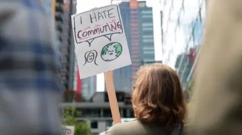 Getty Images A woman protests outside an Amazon office, holding a sign that reads 