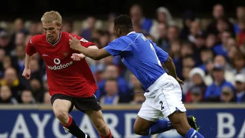 Getty Images Luke Chadwick, wearing red shirt and black shorts and socks of Manchester United with Vodafone sponsor's logo, runs away from defender Fabian Wilnis, of Ipswich Town, wearing blue shirt and socks and white shorts.
