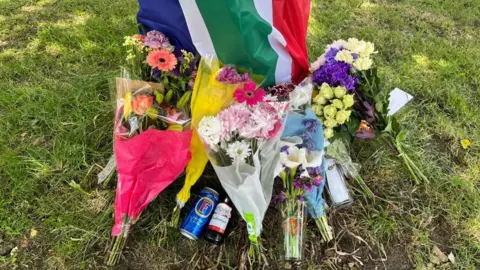 Nicola Haseler/BBC Flowers left by a tree at Ickleford Sports & Recreation Club on Chambers Lane