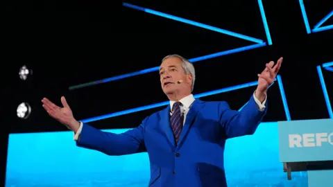 Nigel Farage with arms wide open, greets the crowd at a Reform rally