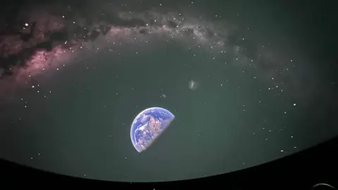 The planetarium screen showing half of the earth and surrounding stars