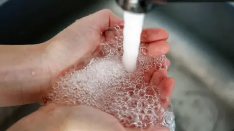 Shutterstock Water runs from a tap into a pair of cupped hands