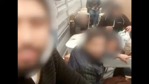 NCA Migrants in the back of a lorry. Their faces are blurred.