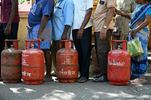 AFP via Getty Images People queue to buy liquefied petroleum gas (LPG) cylinders for domestic use, at a gas agency office in Chennai.