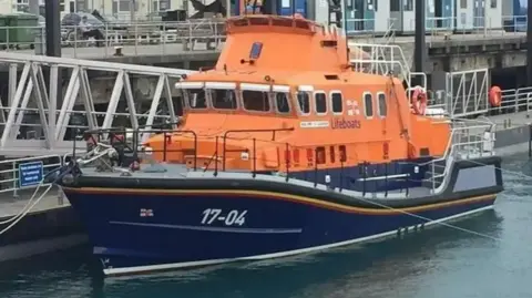 BBC The Spirit of Guernsey St Peter Port Lifeboat at the dock. It is orange and navy blue.