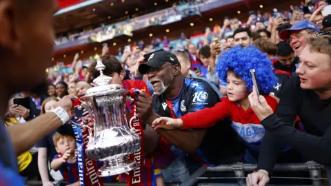 EPA Supporters of Crystal Palace celebrate with the trophy after winning the FA Cup Final.